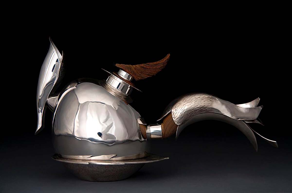 A stylized wood and sterling silver tea kettle symbolizing a rooster.  