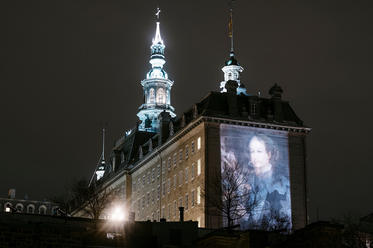 An image projected on the side of a building at night. 