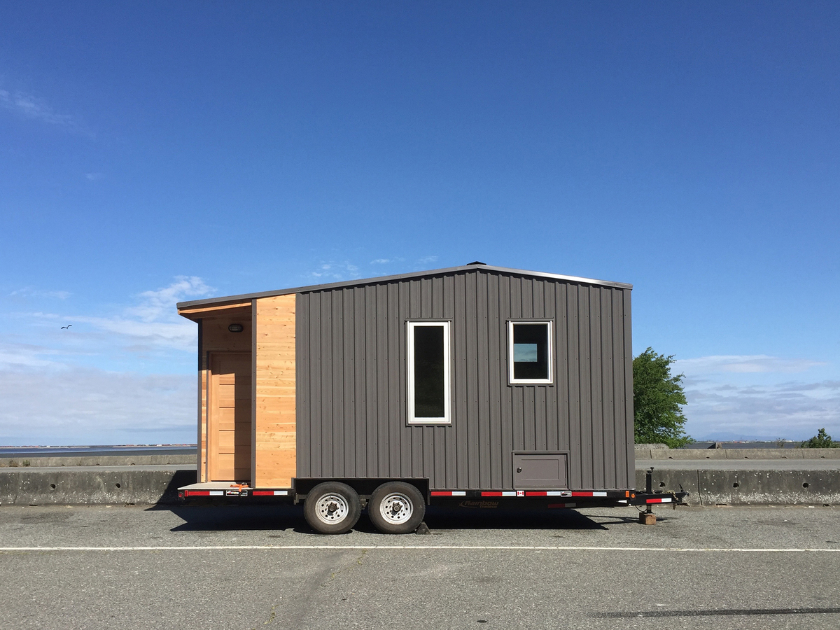 A photo shows a small house built on a trailer. 
