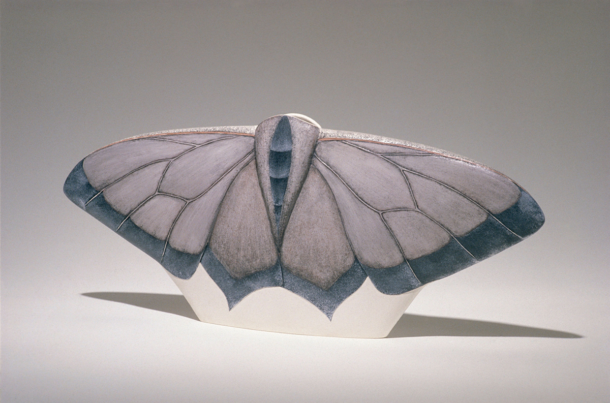 A wide ceramic vessel, in the figure of a moth with wings outstretched, glazed in muted tones. 