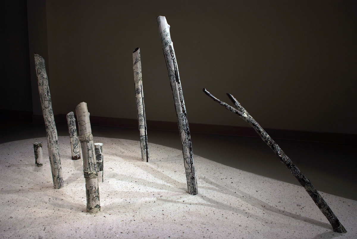 Porcelain figures of eight slender tree trunks in neutral tones rise from a floor of coarse salt crystals against a background of a darkened room. 