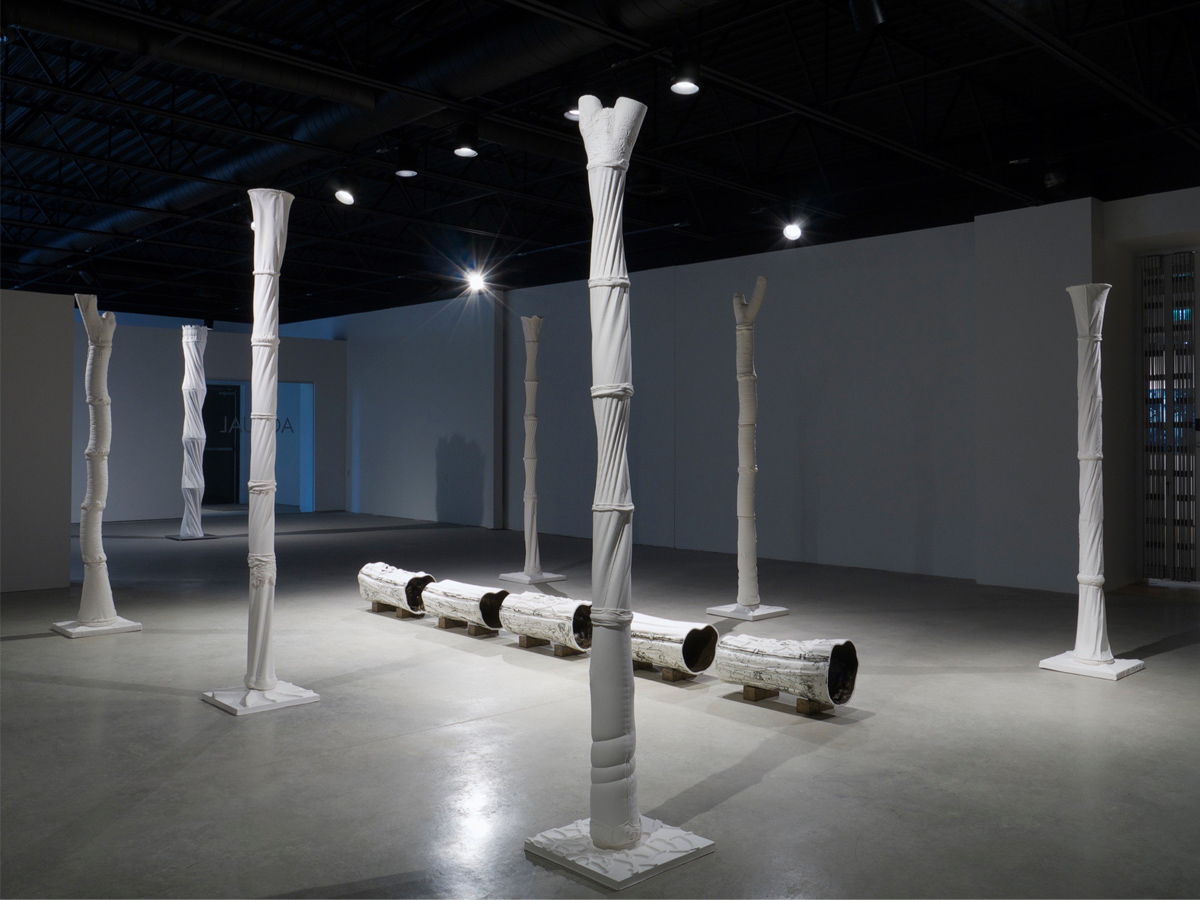 Six tall and slender columns of unglazed porcelain, punctuated by horizontal bands, stand in a two-by-three rectilinear plan. 