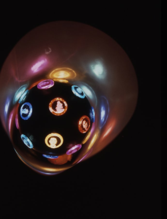 Black ball with tiny illuminated human faces. 