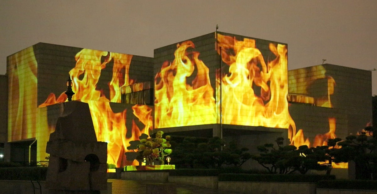 Several buildings covered in projections of flames.  