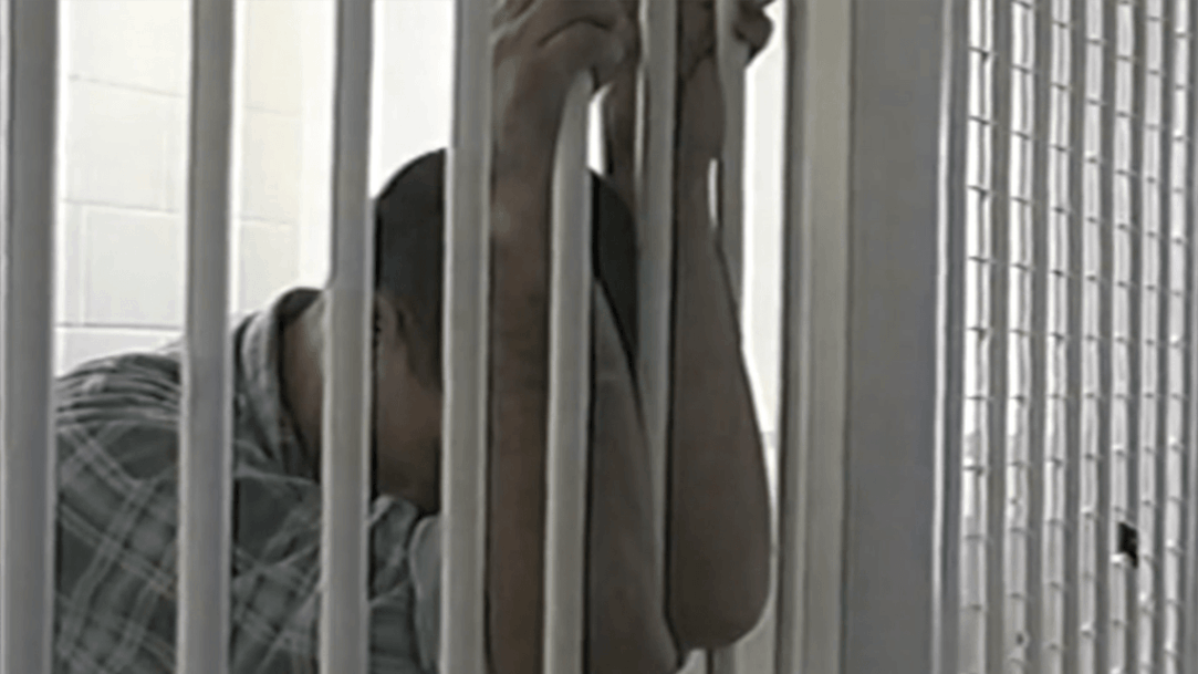 A man hanging onto prison cell bars. 